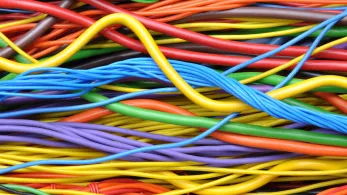 Colorful, intertwined cables in close-up view with protective fire resistant insulation. The cables appear in shades of orange, yellow, green, blue, and red.