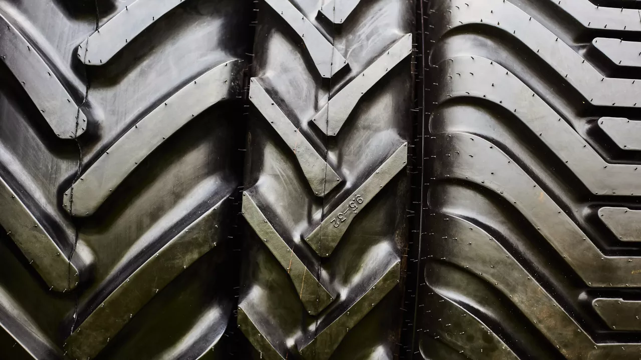 Close-up of large, heavy-duty tires with deep tread patterns, showing intricate designs and textures, suitable for industrial or off-road vehicles.