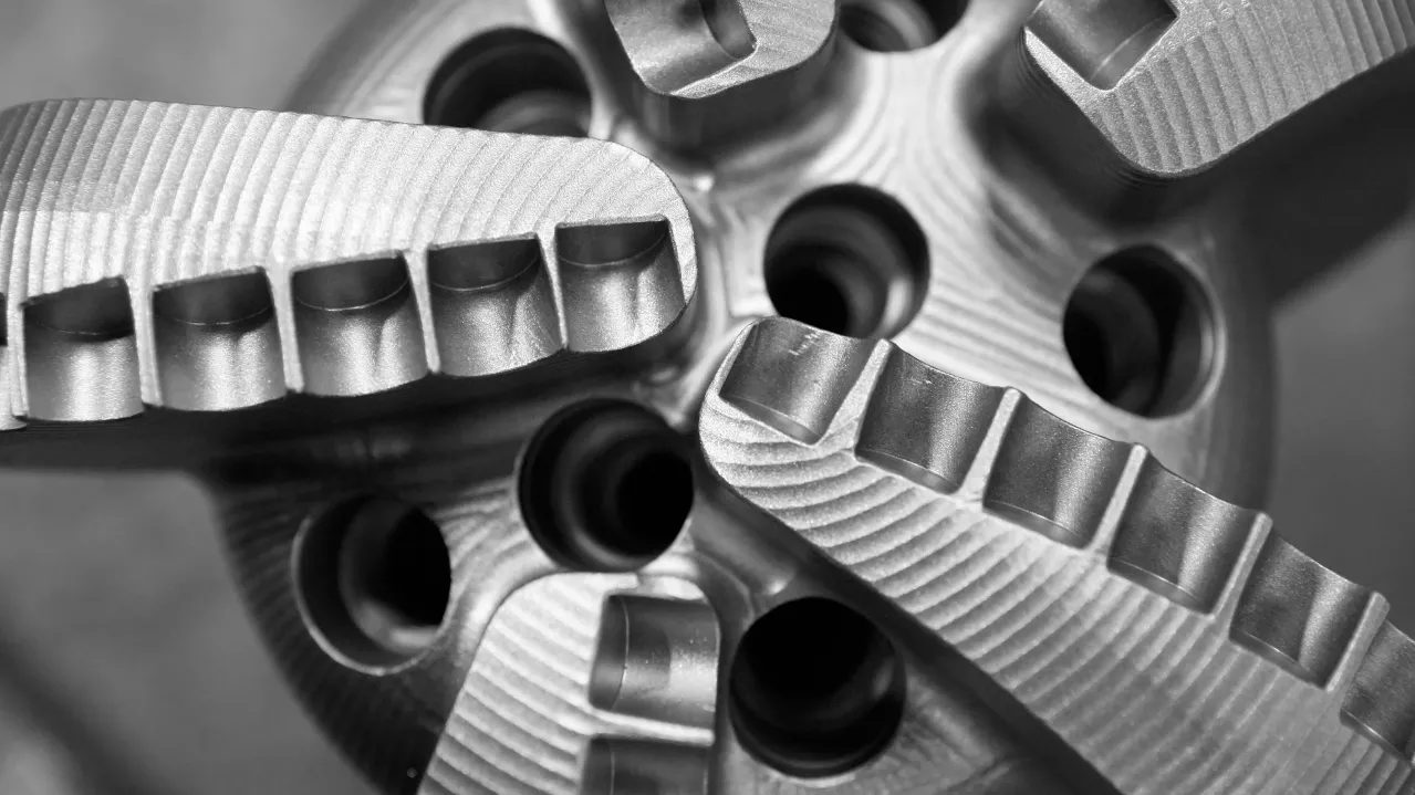 Close-up of interlocking metal gears with detailed textures on a gray scale, highlighting the precision and engineering of mechanical components.