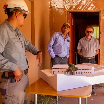 Leader and community representatives gathered around an architectural model of a site.