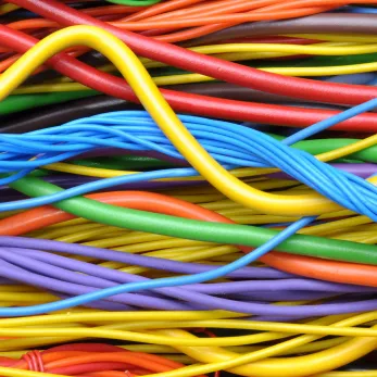 Colorful, intertwined cables in close-up view with protective fire resistant insulation. The cables appear in shades of orange, yellow, green, blue, and red.