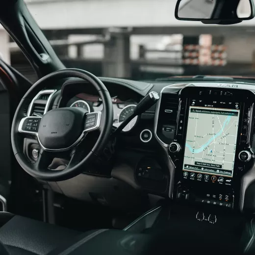 Interior view of a modern car showcasing the steering wheel with a logo and a large touchscreen display on the dashboard.