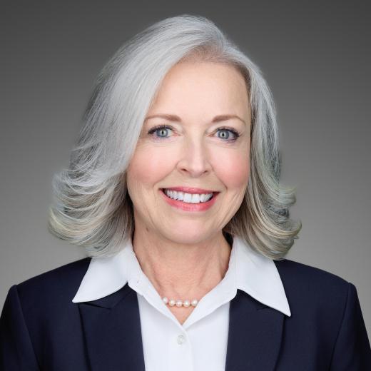 Headshot of Cynthia Lima Senior Vice President, Chief External Affairs and Communications Officer who is smiling, is dressed in a dark suit with a white shirt, with long wavy hair.