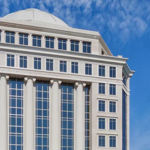 Image of the exterior of Albemarle's Charlotte headquarters. A neoclassical style building with tall columns and a large dome under a clear blue sky. The facade features rows of large windows and intricate detailing.