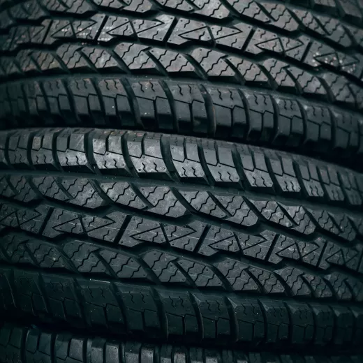 Close-up of a stack of car tires showcasing detailed tread patterns in a moody, monochrome tone.