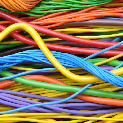 Colorful, intertwined cables in close-up view with protective fire resistant insulation. The cables appear in shades of orange, yellow, green, blue, and red.
