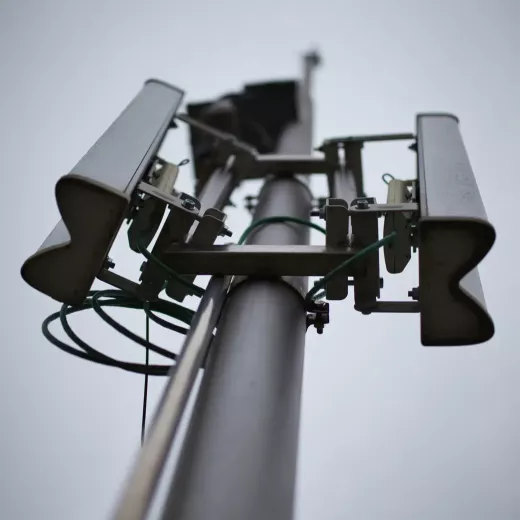 Low-angle view of a telecommunications tower with multiple antennas, cables, and mounting brackets for reliable communications.