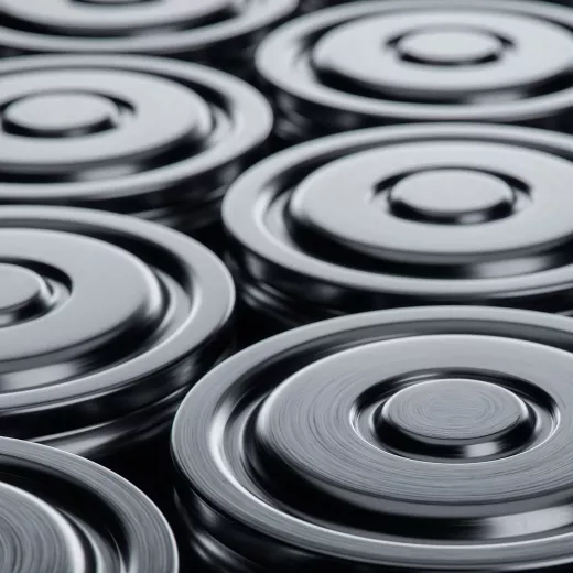 Close-up view of multiple electric vehicle battery cells from a top perspective, highlighting their circular lids and concentric ring patterns.