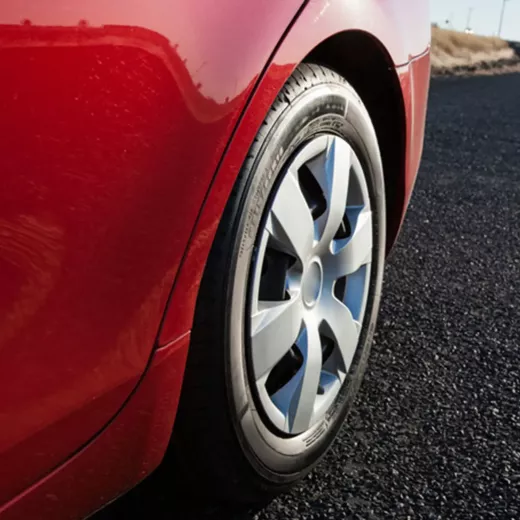 Close-up of a red car's rear wheel on an asphalt road.